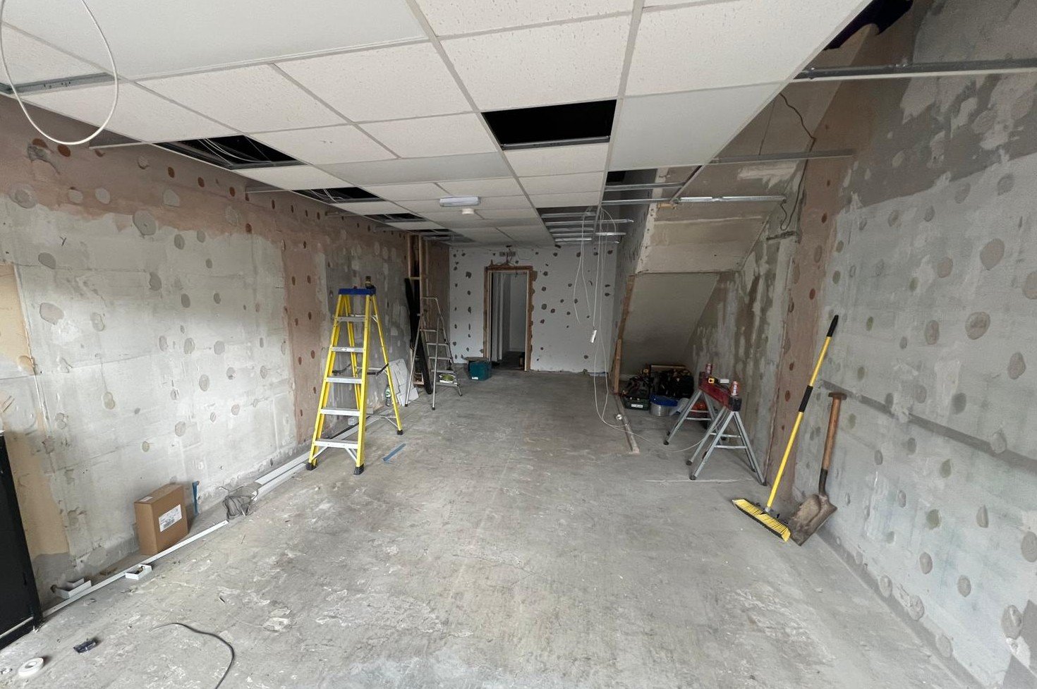 The Audibility clinic unit during August 2024 strip-out, showing exposed walls, ladders, tools and construction materials as the build began.