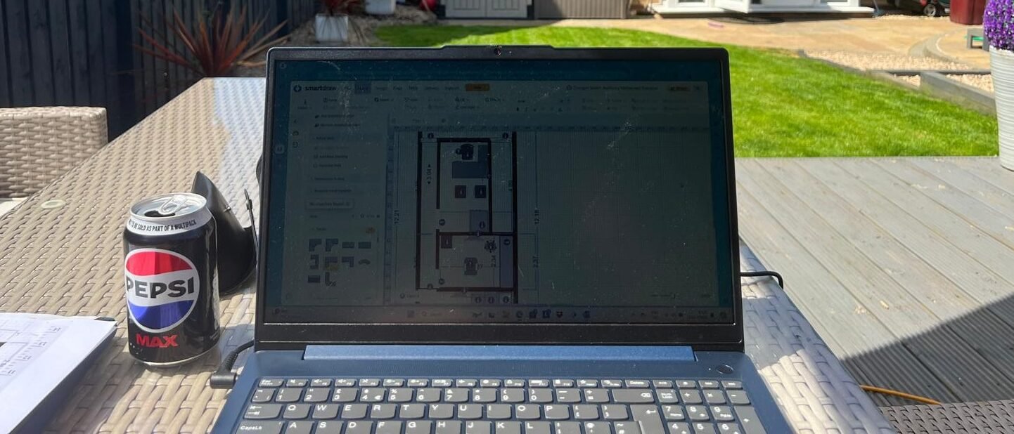 Michael Marchant designing the initial Audibility clinic layout on a laptop while working outdoors in July 2024.