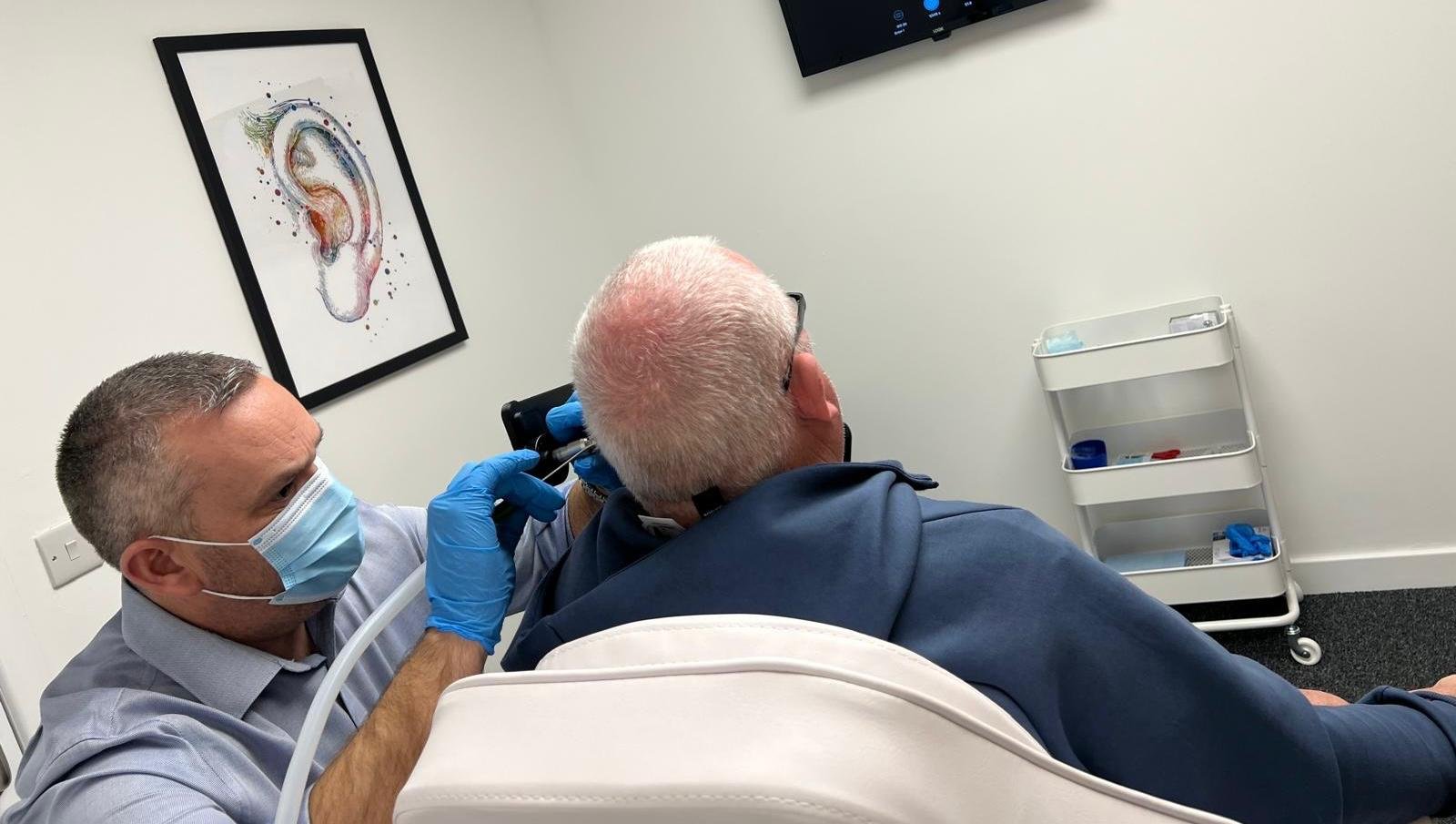 Michael Marchant performing safe microsuction ear wax removal using an ENT‑grade endoscope at Audibility Hearing Centre in Motherwell.